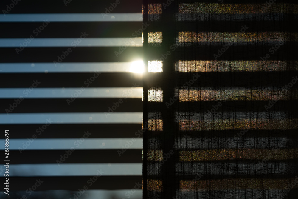 The sun shining through blinds, shades and a curtain. With a blue sky during springtime. The sun shining through blinds, shades and a curtain. With a blue sky during springtime.