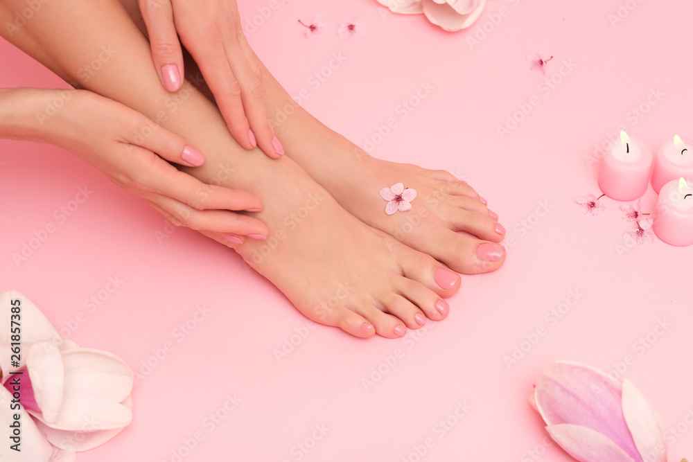 Beautiful shoot of female hands and feet on pink background surrounded by magnolia pink flowers. Beautiful shoot of female hands and feet on pink background surrounded by magnolia pink flowers.