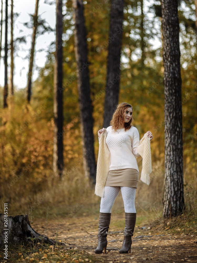 red-haired girl in bright clothes against a background of tree trunks in the autumn forest red-haired girl in bright clothes against a background of tree trunks in the autumn forest