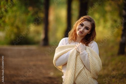red-haired girl in bright clothes on a background of autumn forest on a sunny day