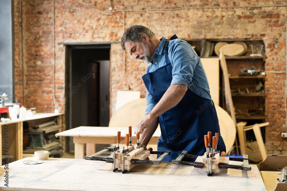 Mature handsome joiner work in carpentry. He is successful entrepreneur at his workplace. Mature handsome joiner work in carpentry. He is successful entrepreneur at his workplace.