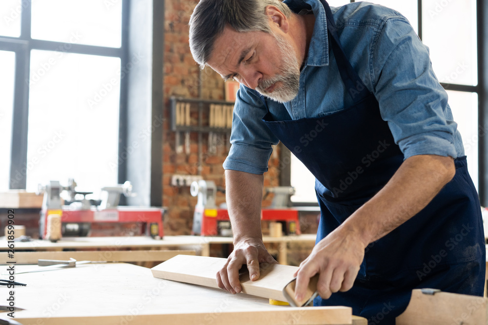 Mature handsome joiner work in carpentry. He is successful entrepreneur at his workplace. Mature handsome joiner work in carpentry. He is successful entrepreneur at his workplace.
