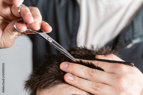 Close-up Hair cutting with metal scissors. Master cuts hair and beard of men in the barbershop, hairdresser makes hairstyle for a young man