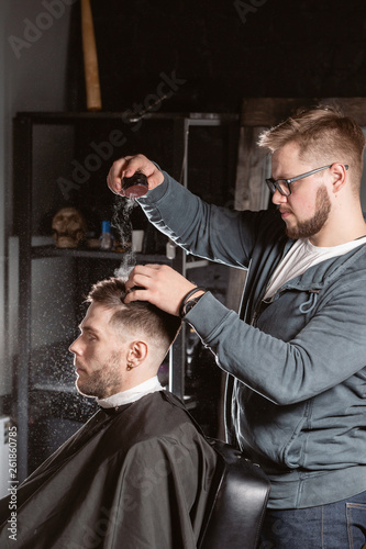 Master barber pours out styling powder to fix hair. hairdresser makes hairstyle for a young man.