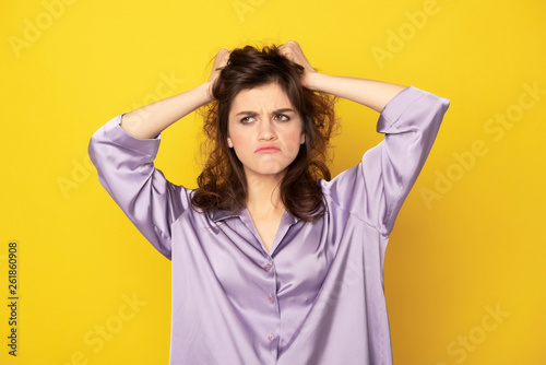 Annoyed young girl in pajamas grasping her hairs