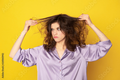 Annoyed young girl looking on her rumpled hairs