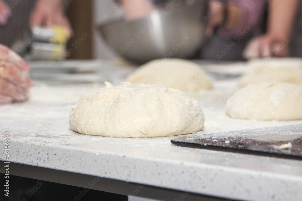 Cooks roll the dough for baking, pieces of raw dough on the Board Cooks roll the dough for baking, pieces of raw dough on the Board