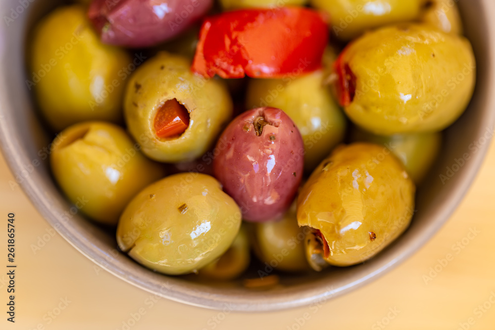 Olives stuffed with red pepper and spices of herbs. Multi-colored olives in a gray bowl on a rustic table. Blurry background. Macro. Image doesn’t in focus. Top view. Olives stuffed with red pepper and spices of herbs. Multi-colored olives in a gray bowl on a rustic table. Blurry background. Macro. Image doesn’t in focus. Top view.