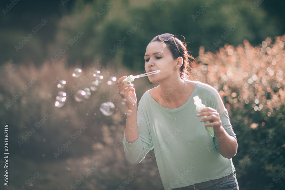 beautiful young woman blowing soap bubbles in the Park Sunny beautiful young woman blowing soap bubbles in the Park Sunny