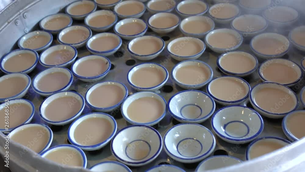 Filling thuai talai cups with coconut milk mixture; making Khanom Thuai dessert. Filling thuai talai cups with coconut milk mixture; making Khanom Thuai dessert.