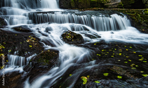 Cascading waterfall of milky white water pours over the dark rock surface in the Pacific Northwest area of Oregon. This image was captured with a slow shutter speed making a static slow motion image.