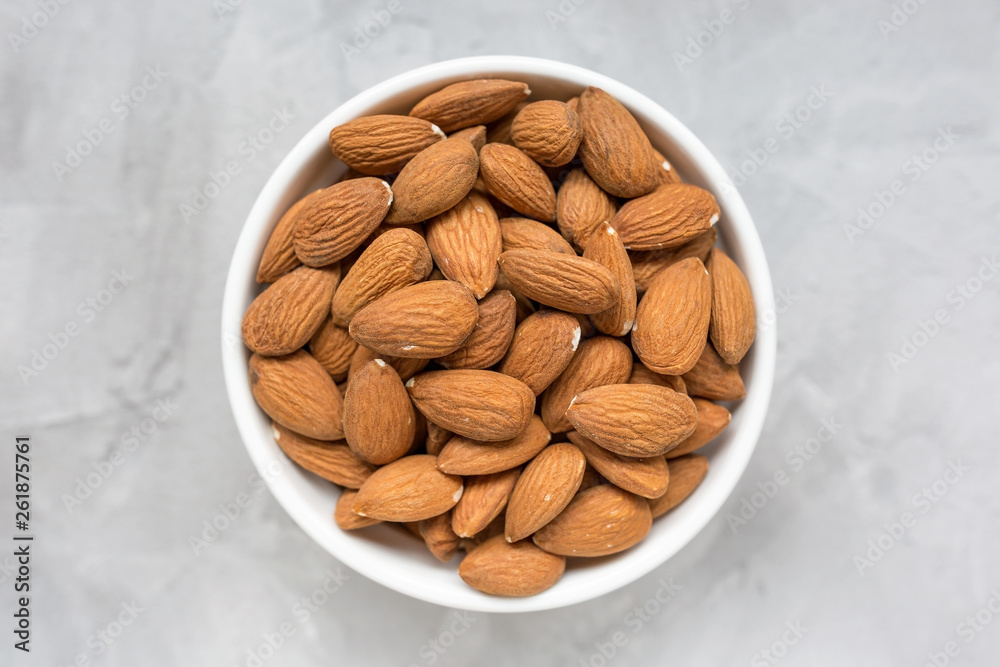 Raw almonds in a porcelain bowl on a gray background Raw almonds in a porcelain bowl on a gray background