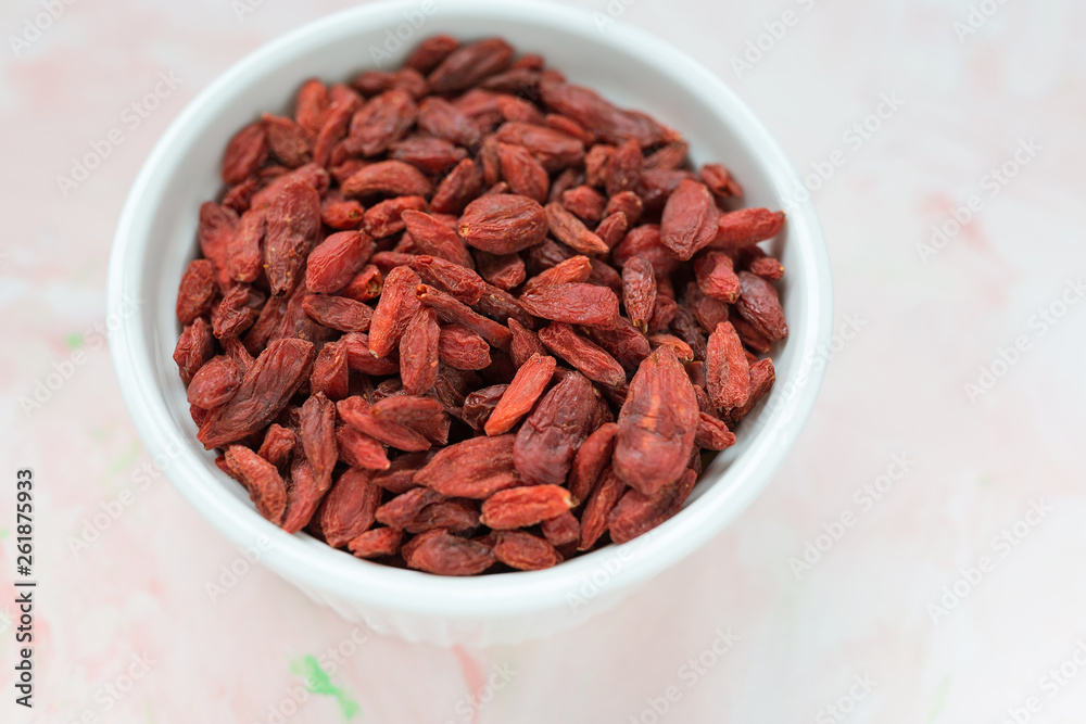 Dried goji berries in a porcelain bowl on a pink background Dried goji berries in a porcelain bowl on a pink background