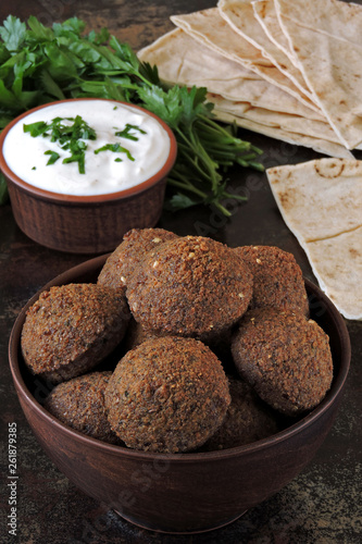 Fresh homemade falafel in a bowl with sauce, parsley and pita. Middle Eastern cuisine.