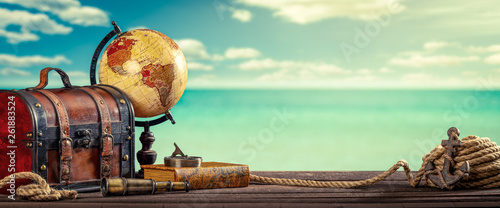 Vintage World Globe, Suitcase, Compass, Telescope, Book, Rope And Anchor On Dock With Water Clouds And Sky Background - Travel Concept