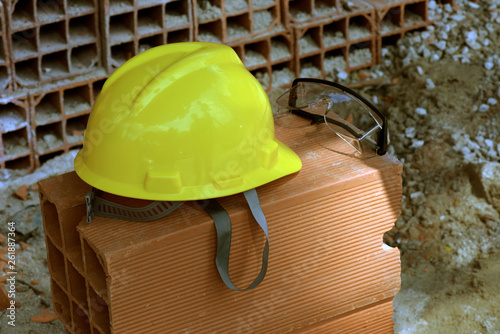 Yellow protective helmet on pile of red bricks