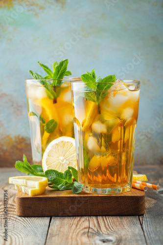 Bild auf Leinwand Traditional iced tea with lemon and ice in tall glasses on a wooden rustic table