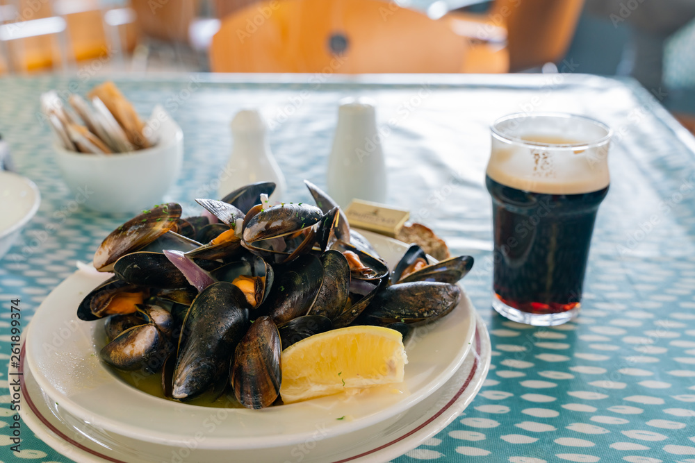 Fototapeta premium Close up shot of a glass of dark beer and a dish of mussels
