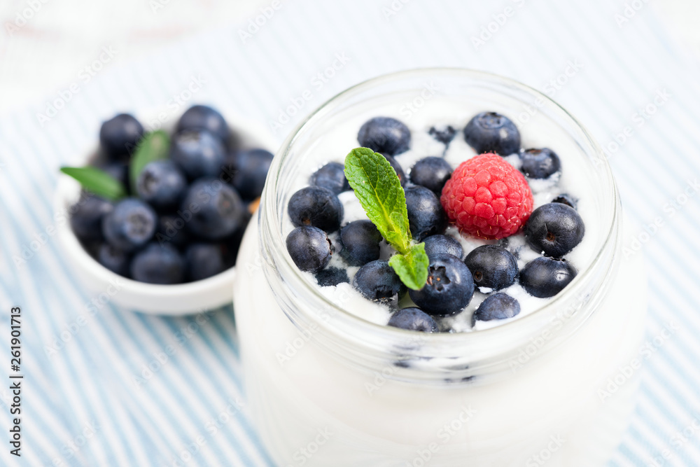 Yogurt with blueberies in jar, closeup view. Rich in Calcium and Protein greek yogurt topped with fresh blueberries, raspberry and mint leaf Yogurt with blueberies in jar, closeup view. Rich in Calcium and Protein greek yogurt topped with fresh blueberries, raspberry and mint leaf