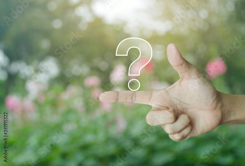 Question mark sign icon on finger over blur pink flower and tree in park, Business customer service and support concept