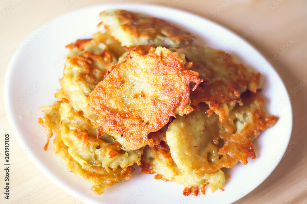 Homemade potato pancakes in a white plate on a wooden table Homemade potato pancakes in a white plate on a wooden table