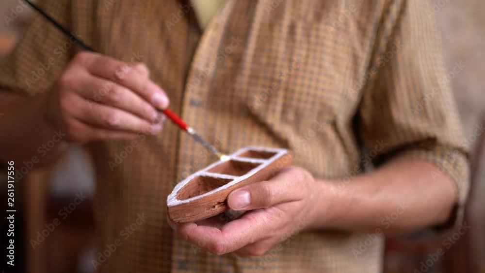 Craftsman painting ship figures in workshop Craftsman painting ship figures in workshop