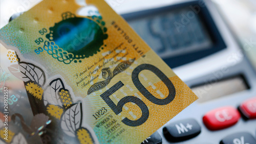 Australian fifty dollar bill over a calculator. The new 2019 issue is designed to deter counterfeiting, the note is polymer and water resistant with a clear holographic strip photo