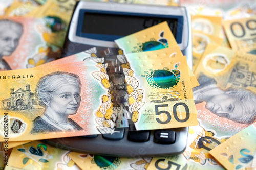 Australian fifty dollar bill over a calculator. The new 2019 issue is designed to deter counterfeiting, the note is polymer and water resistant with a clear holographic strip photo