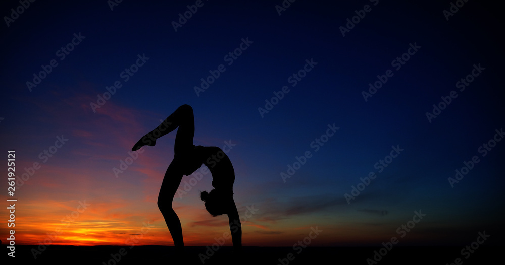 dancer in the dance does the splits in the air against the sunset.
