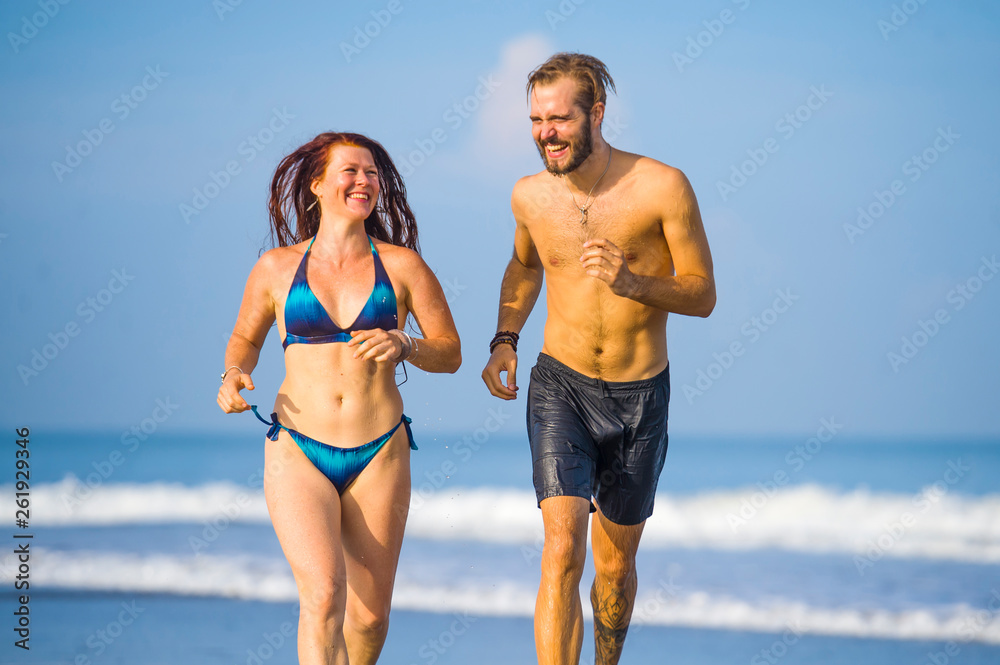beautiful couple enjoying Summer holidays travel or honeymoon trip together in tropical paradise beach having fun running carefree and playful on the sea