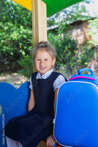 An elementary school student is sitting on the playground.