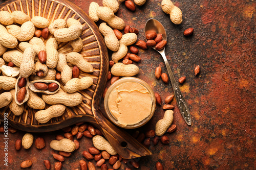 Board with tasty peanut butter and nuts on color background © Pixel-Shot
