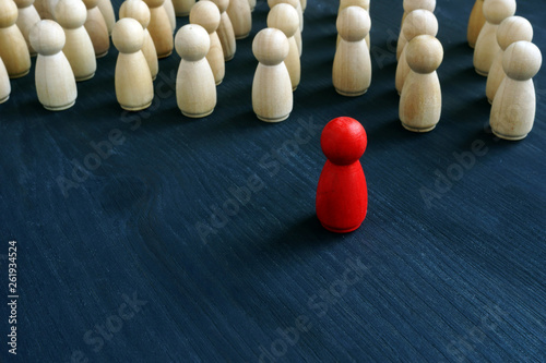 Red figurine in front of line as symbol of leadership. Stand out from the crowd concept.