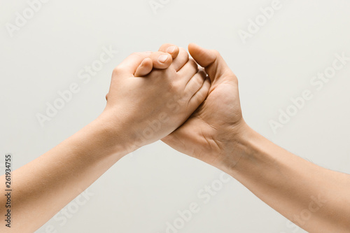 Don't fight, let's be friends. Two male hands competion in arm wrestling isolated on grey studio background. Concept of standoff, support, friendship, business, community or strained relations.