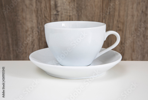 White mug and saucer on a wooden table.