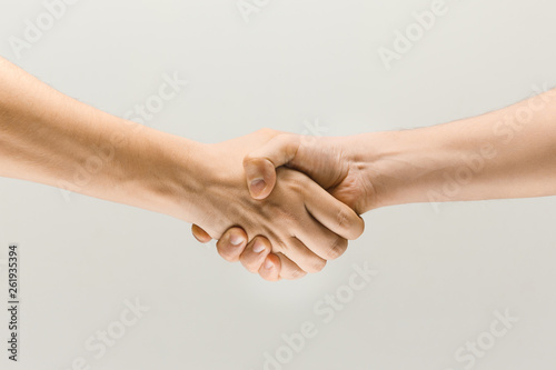 Friend's greetings. Teamwork and communications. Two male hands shaking isolated on grey studio background. Concept of help, partnership, friendship, relation, business, togetherness.