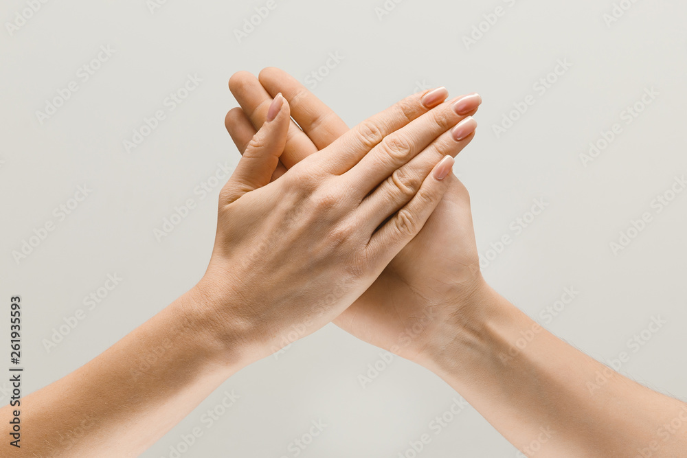 Say hello to the new meetings. Male and female hands demonstrating a gesture of getting touch or greetings isolated on gray studio background. Concept of human relations, relationship or business. Say hello to the new meetings. Male and female hands demonstrating a gesture of getting touch or greetings isolated on gray studio background. Concept of human relations, relationship or business.