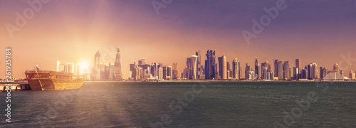 Foto Banner panorama of traditional wooden dhow and towers of the West Bay skyline with sunset sun rays in Doha Bay