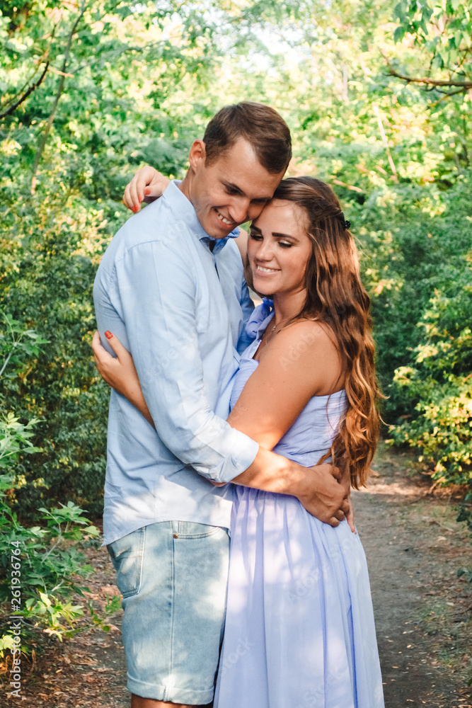 Couple in love smiling and hugging in trees tunnel. Man holding hands around woman. Tender and affectionate couple standing on nature background. Young beautiful couple. Happy couple in love Couple in love smiling and hugging in trees tunnel. Man holding hands around woman. Tender and affectionate couple standing on nature background. Young beautiful couple. Happy couple in love