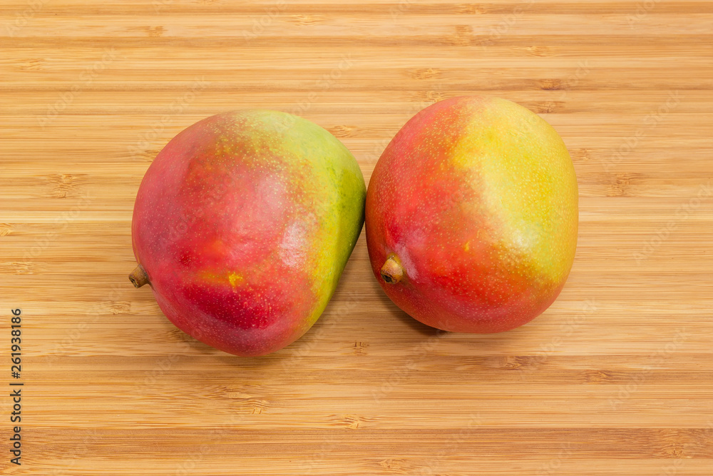 Two whole mango fruits on a wooden surface Two whole mango fruits on a wooden surface