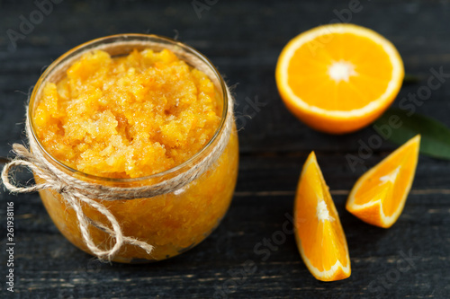 Homemade orange jam on a wooden table with pieces of fruit