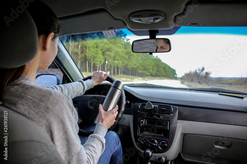 Woman with thermos driving a car