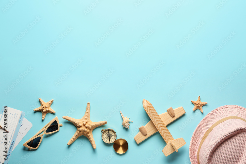 Toy airplane with compass, tickets, seashells and accessories on color