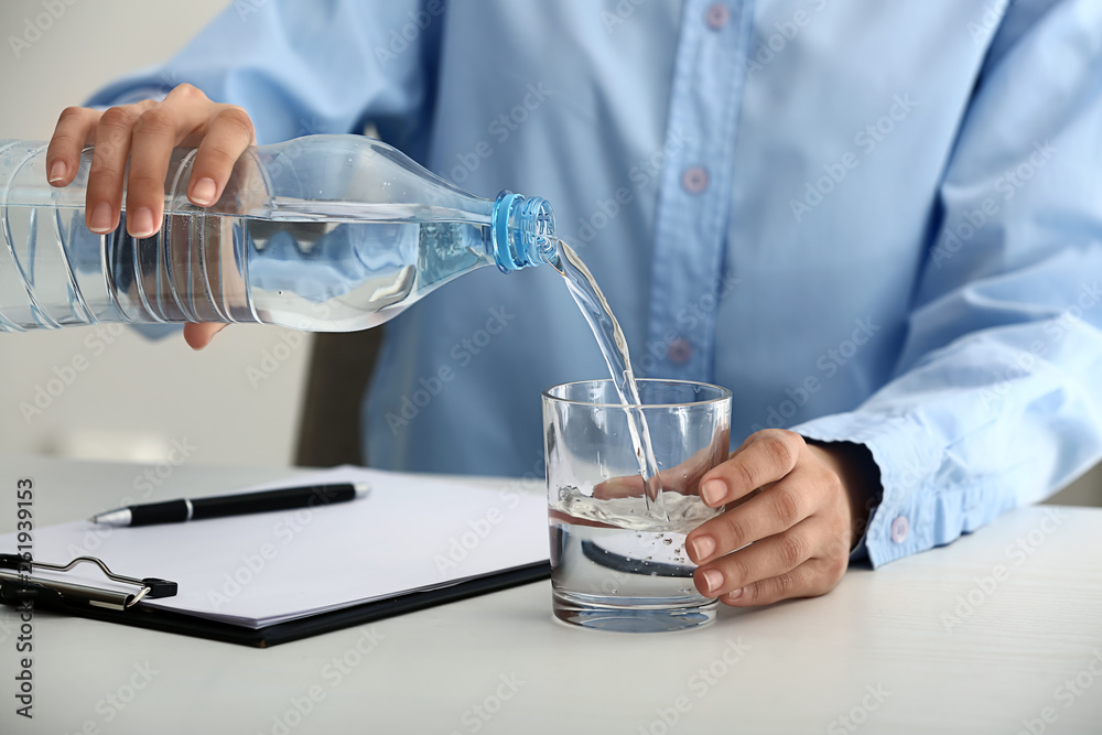 Woman pouring water into glass on table Woman pouring water into glass on table