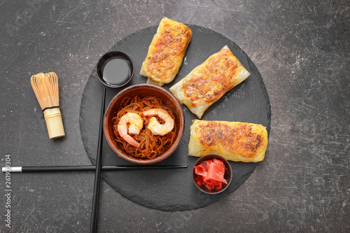 Slate plate with tasty fried spring rolls on table