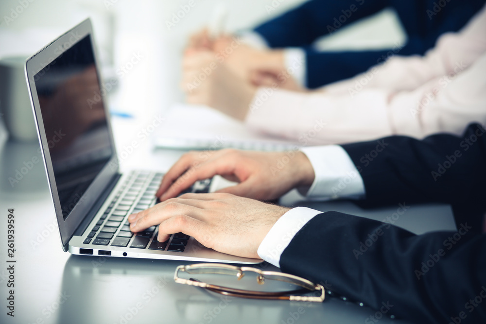 Group of business people working together in office. Man hands typing on laptop computer Group of business people working together in office. Man hands typing on laptop computer