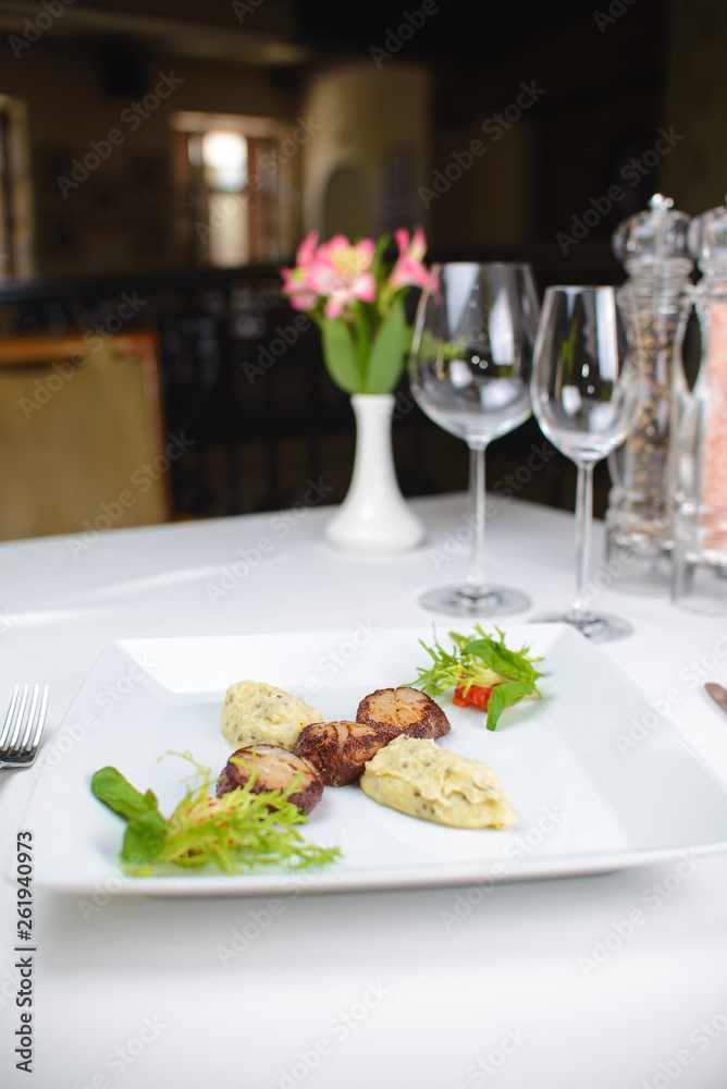 grilled scallops with celery puree and vegetables. on a white plate