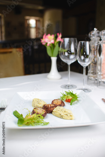 grilled scallops with celery puree and vegetables. on a white plate