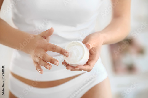 Beautiful young woman with jar of cream at home  closeup