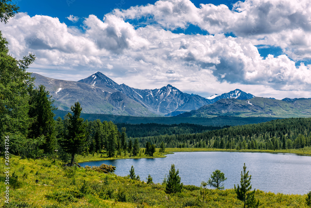 Mountain landscape, white clouds, lake and mountain range in the distance. Fantastic sunny day in mountains, large panorama. Location is in Altai, Russia.